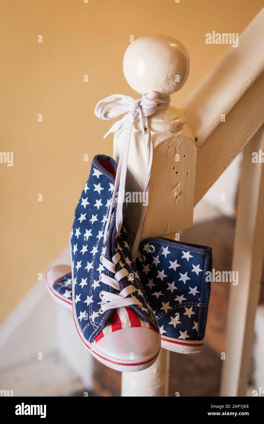 A pair of stars and stripes high-top shoes hanging on a banister Stock Photo