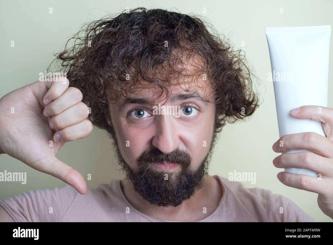 Portrait of a young guy with dirty hair and problematic scalp. Holding