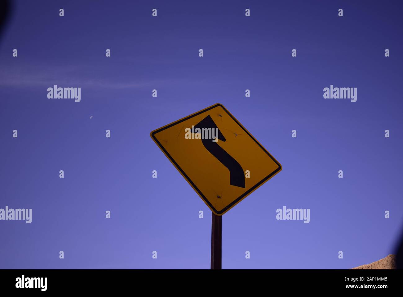 Low Angle Close Up Of Yellow Curve Sign Against Soft Blue Sky Stock Photo