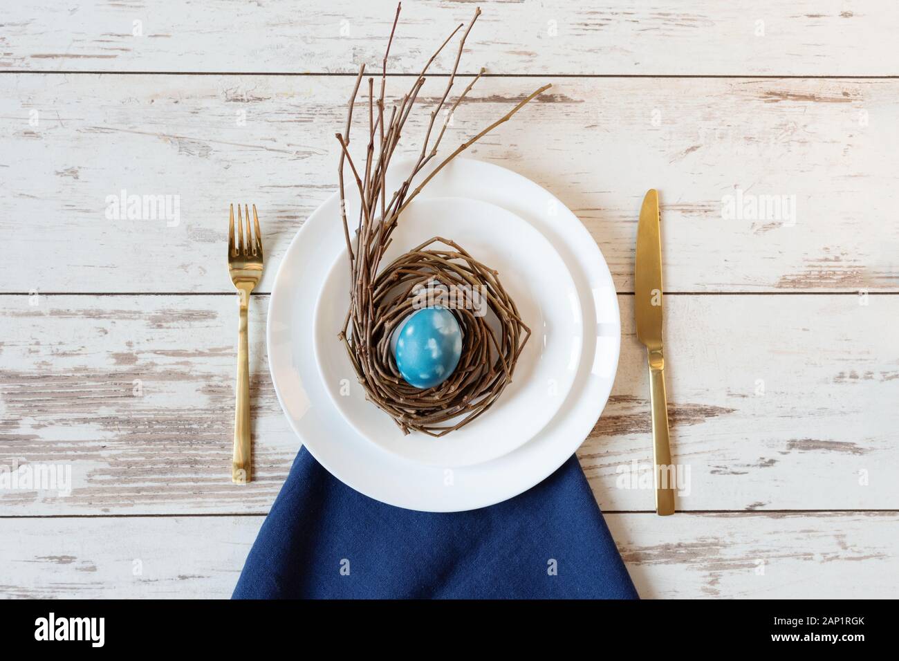 Creative festive Easter table setting on wood background with blue marble colored egg on a nest. Happy Easter time. Stock Photo
