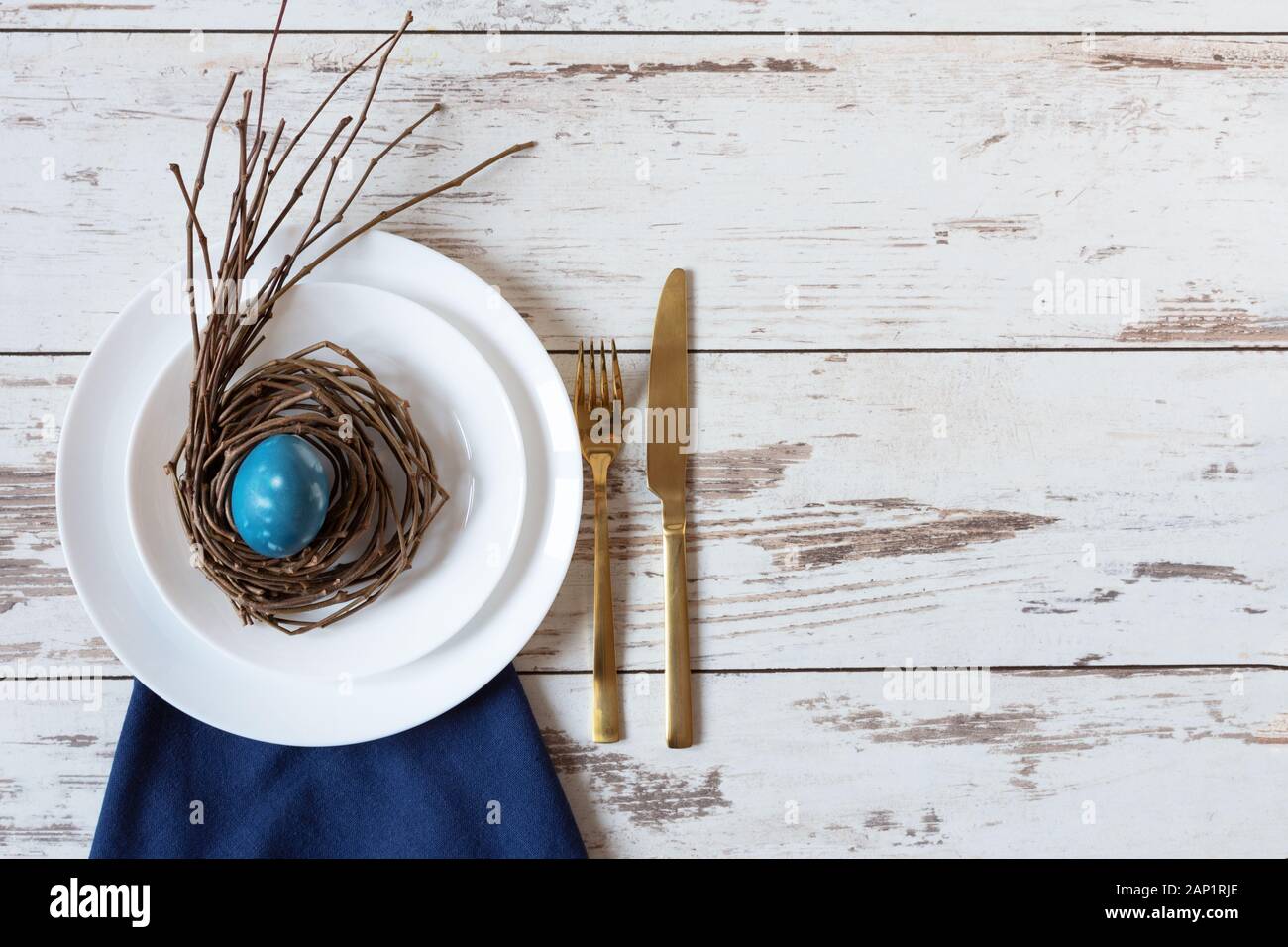 Creative festive Easter table setting on wood background with blue marble colored egg on a nest. Happy Easter time. Stock Photo