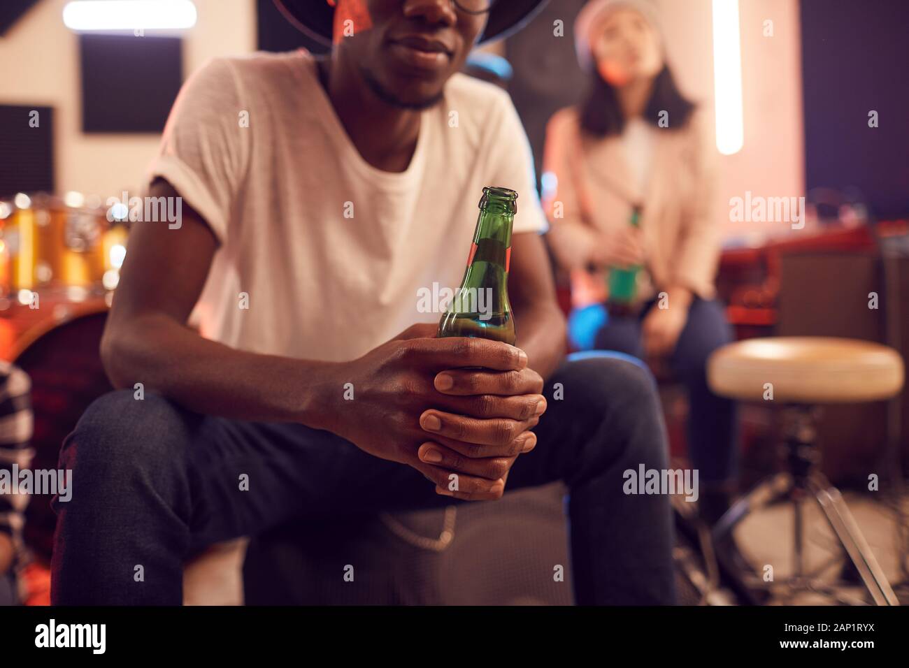 Midsection portrait of trendy African man holding beer bottle while