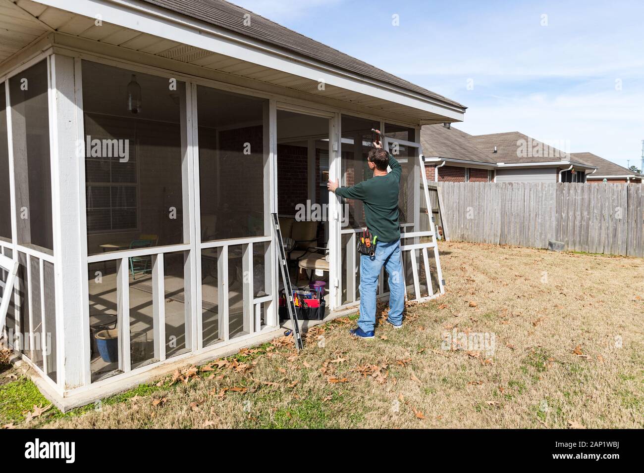 Homeowner works on repairing door to screened in back porch Stock Photo