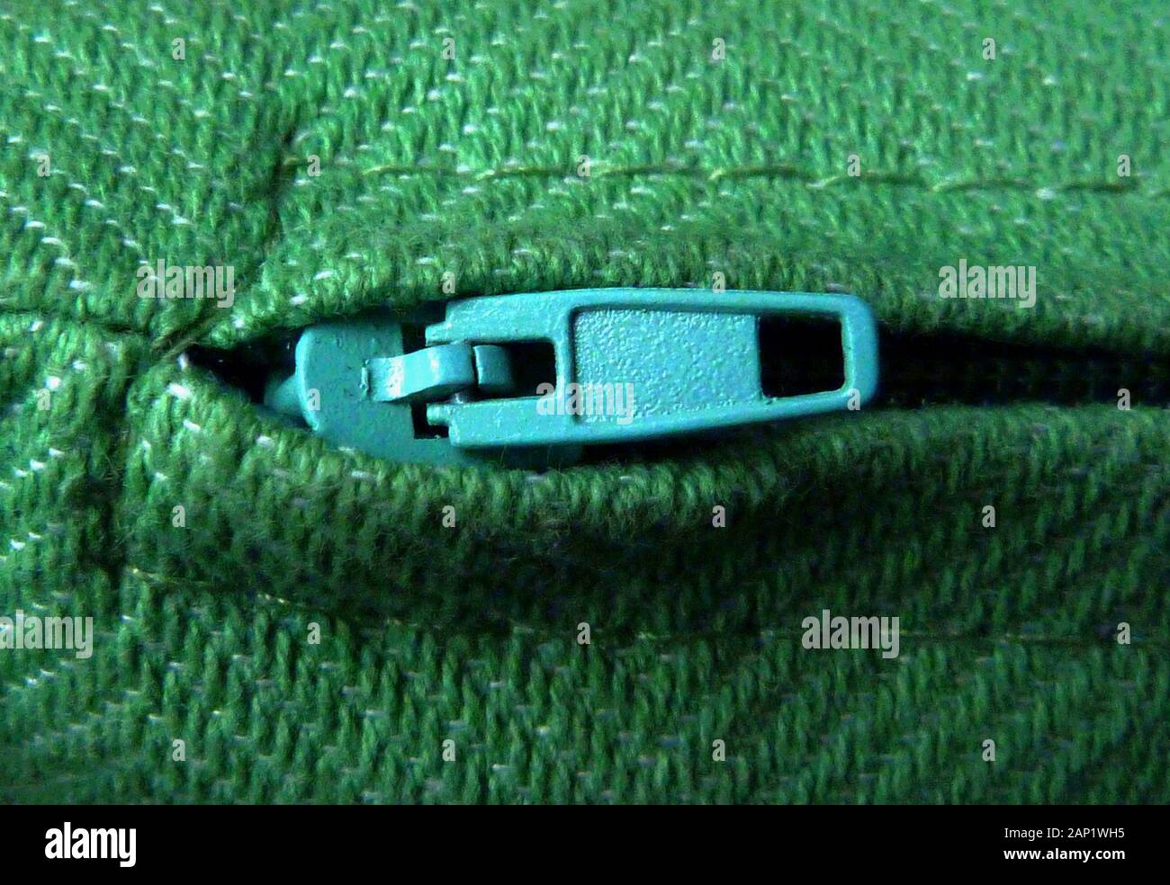 zipper puller macro close up with green wool fabric material and fine stitching. sewing and home decoration concept. fine wool textile thread texture. Stock Photo