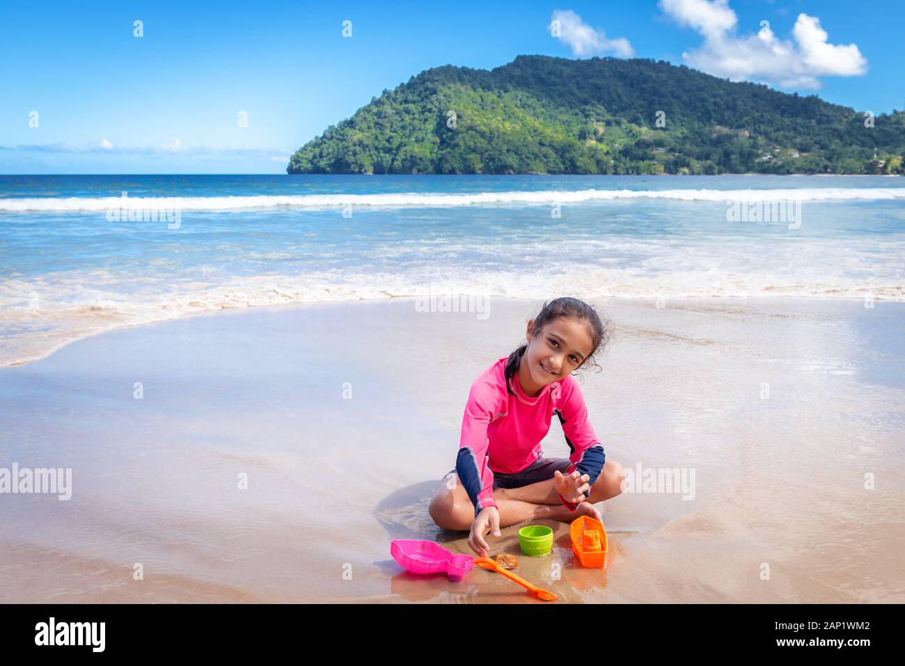 Little girl playing with sand on Maracas Bay Beach Trinidad and Tobago sitting outdoors fun activity smiling Stock Photo