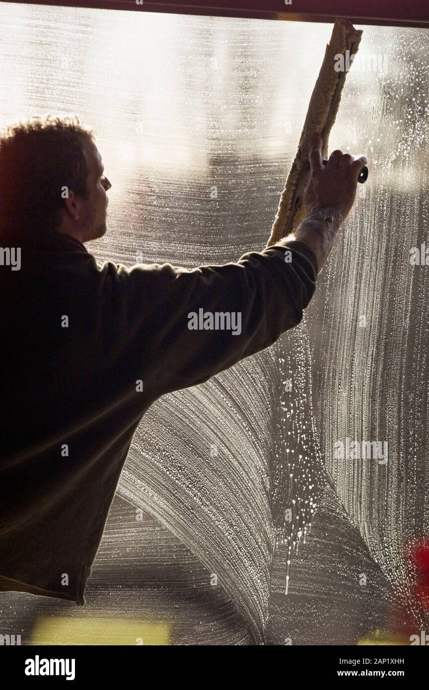 Maintenance worker cleaning a window the large squeegee Stock Photo