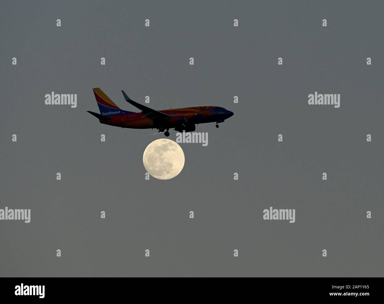 A Southwest Airlines Boeing 737-700 airplane lands over a full moon near Orlando International Airport or MCO. Stock Photo
