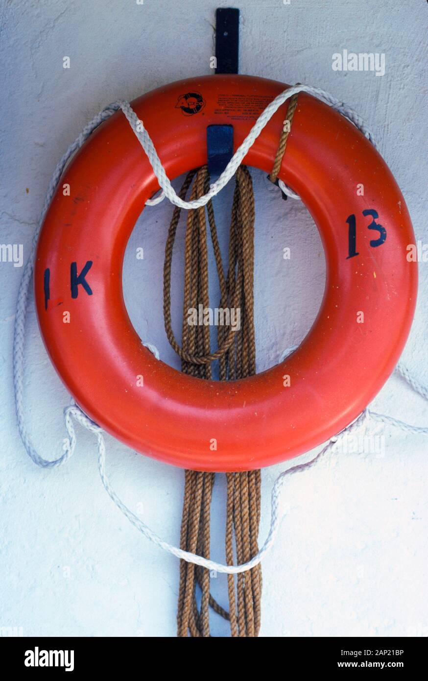Orange life preserver and rope against a white wall Stock Photo