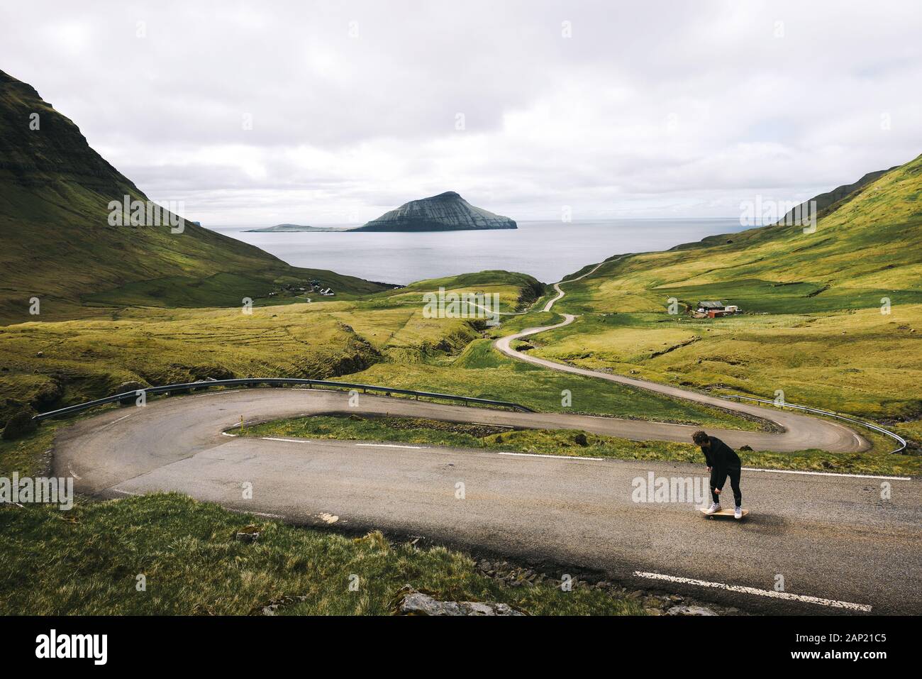 Young skater riding a skateboard through the beatiful scenery of Faroe Islands Stock Photo