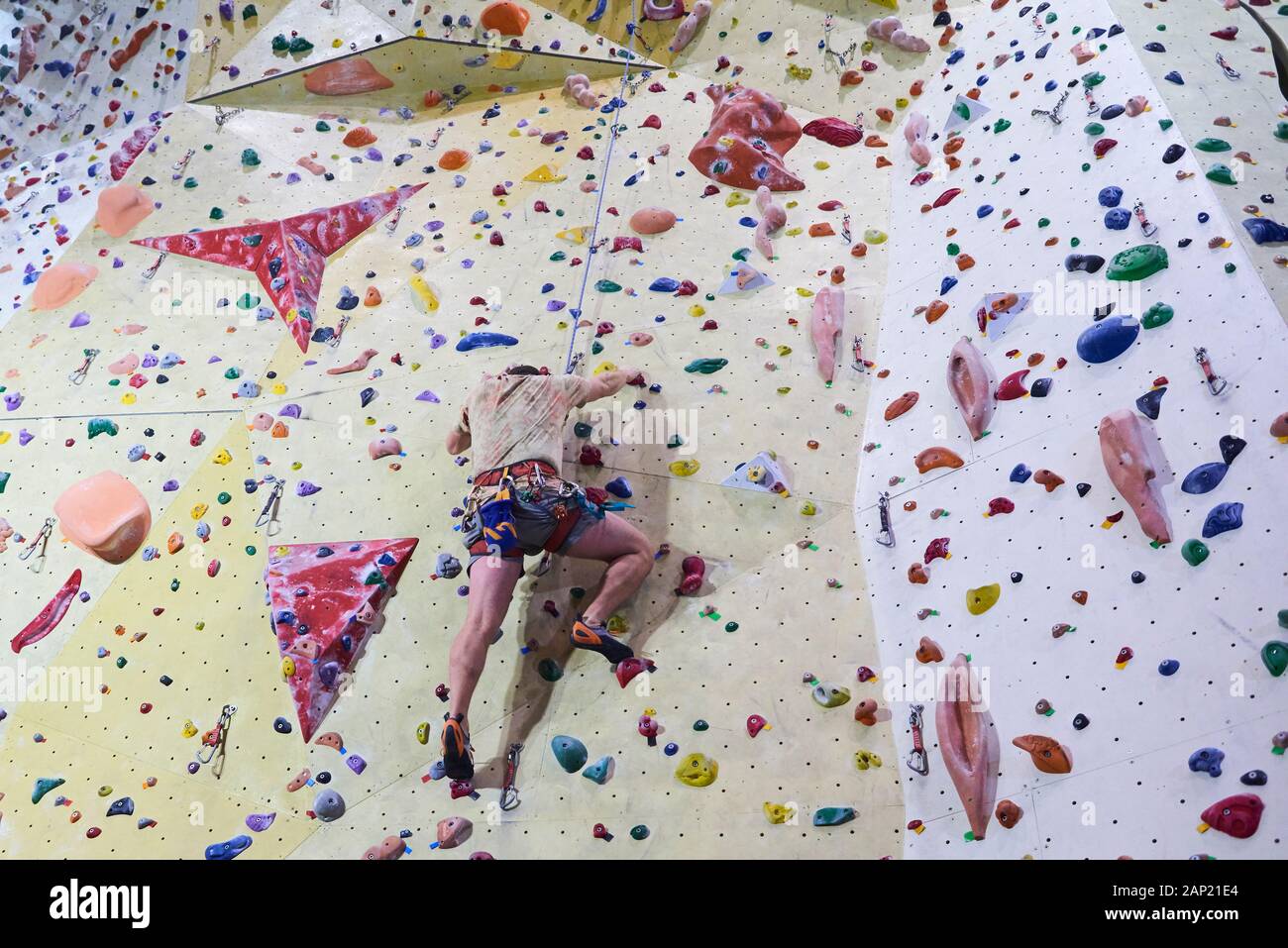 Man climbing wall in bouldering gym. Detail on legs and equipment Stock Photo