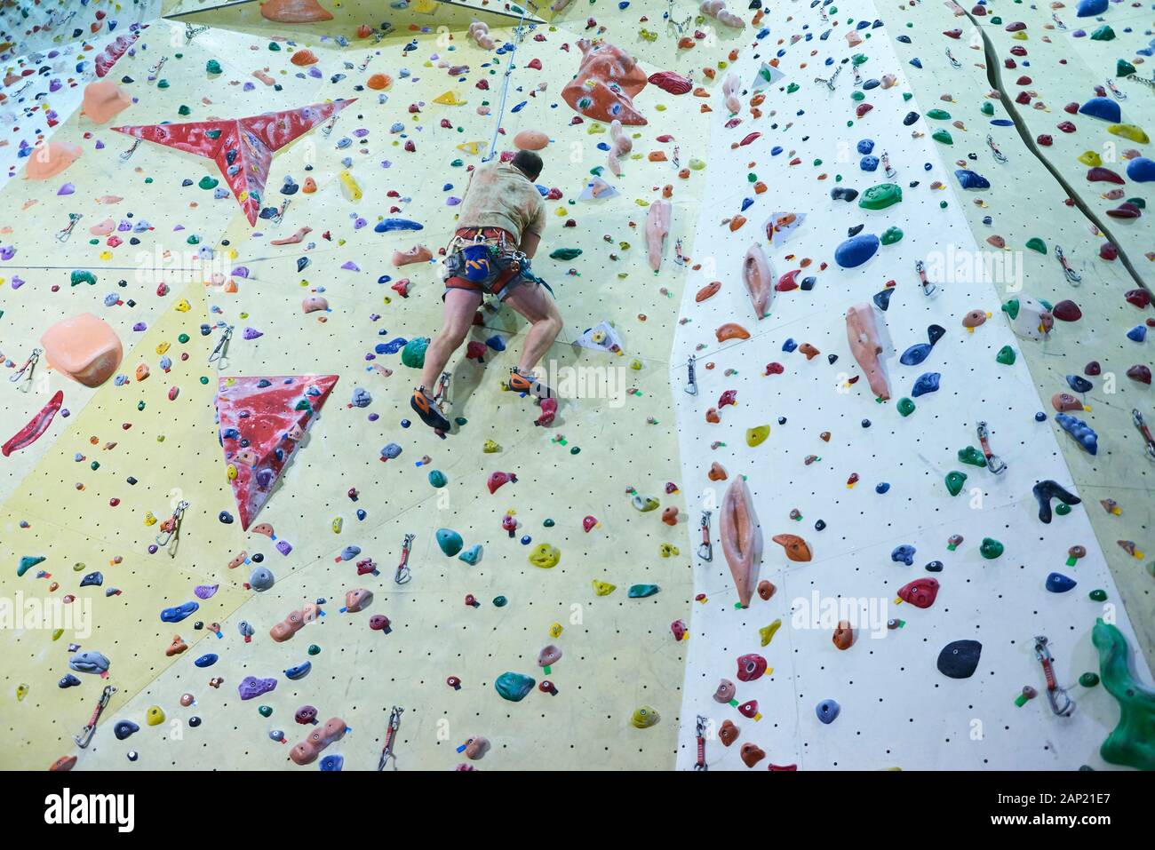 Man climbing wall in bouldering gym. Detail on legs and equipment Stock Photo