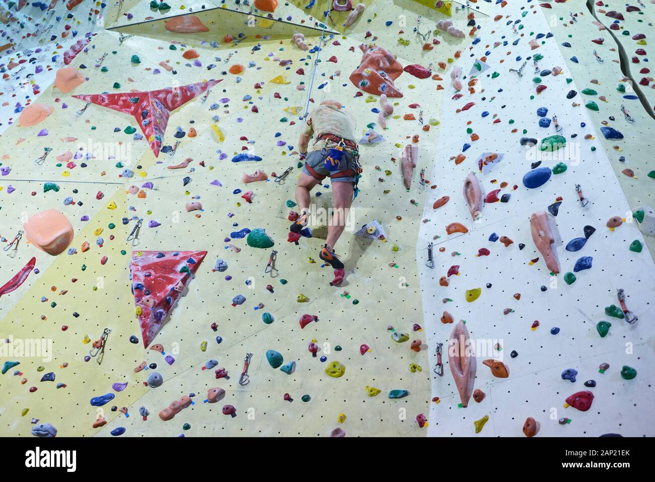 Man climbing wall in bouldering gym. Detail on legs and equipment Stock