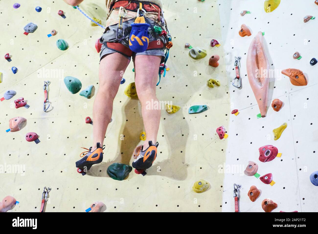 Man climbing wall in bouldering gym. Detail on legs and equipment Stock