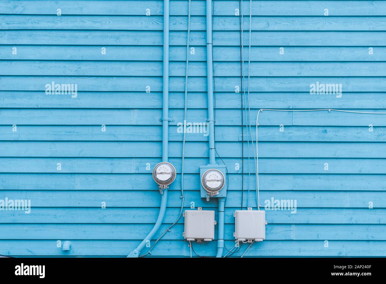 Kilowatt hour meters installed on the wall. Analog electricity meter on pastel blue background. Wooden boards pattern Stock Photo