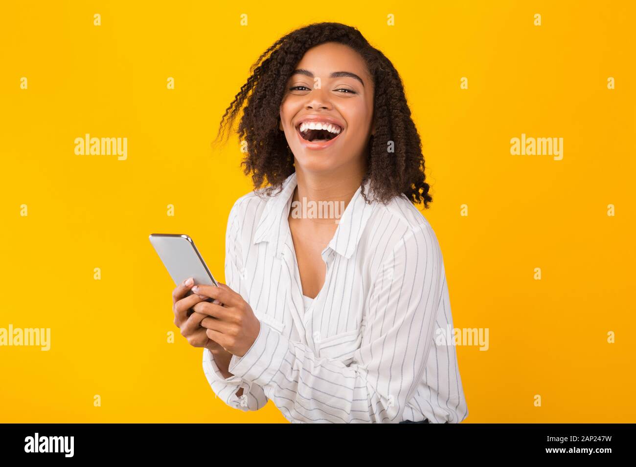 Happy afo girl using cell phone looking at camera Stock Photo