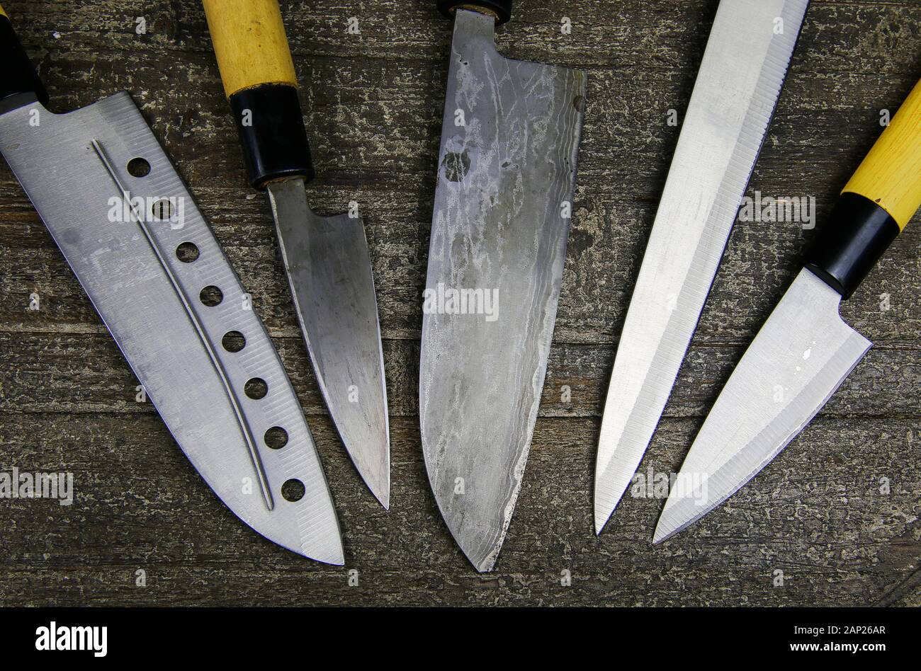 Choice of weapons concept -View on set of japanese and european chef knives on wood table Stock Photo