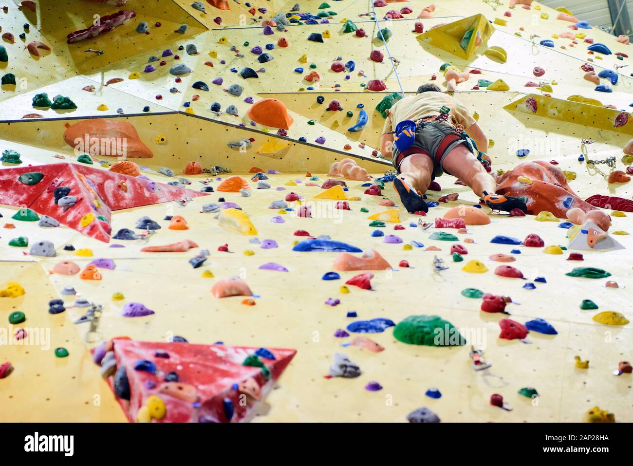 Man climbing wall in bouldering gym. Detail on legs and equipment Stock