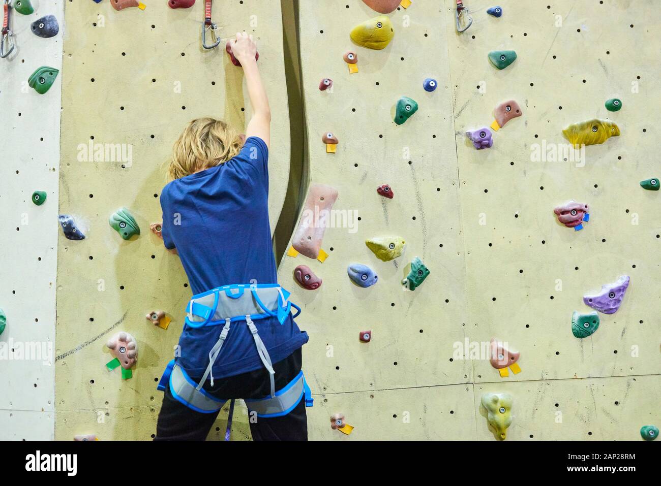 Man climbing wall in bouldering gym. Detail on legs and equipment Stock Photo