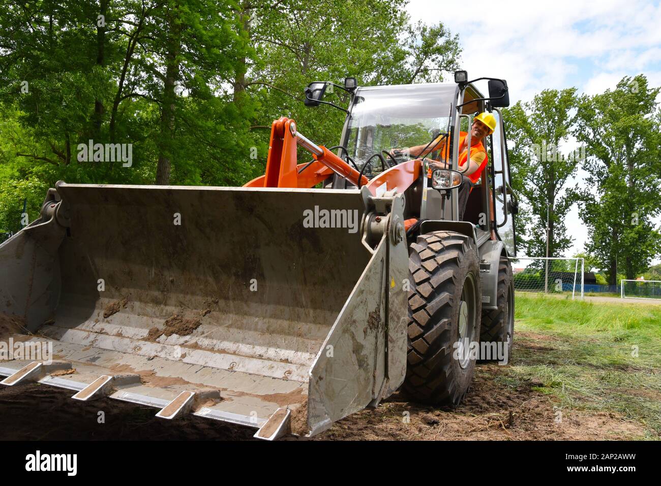 Construction worker drives a small wheel loader on the construction site Stock Photo