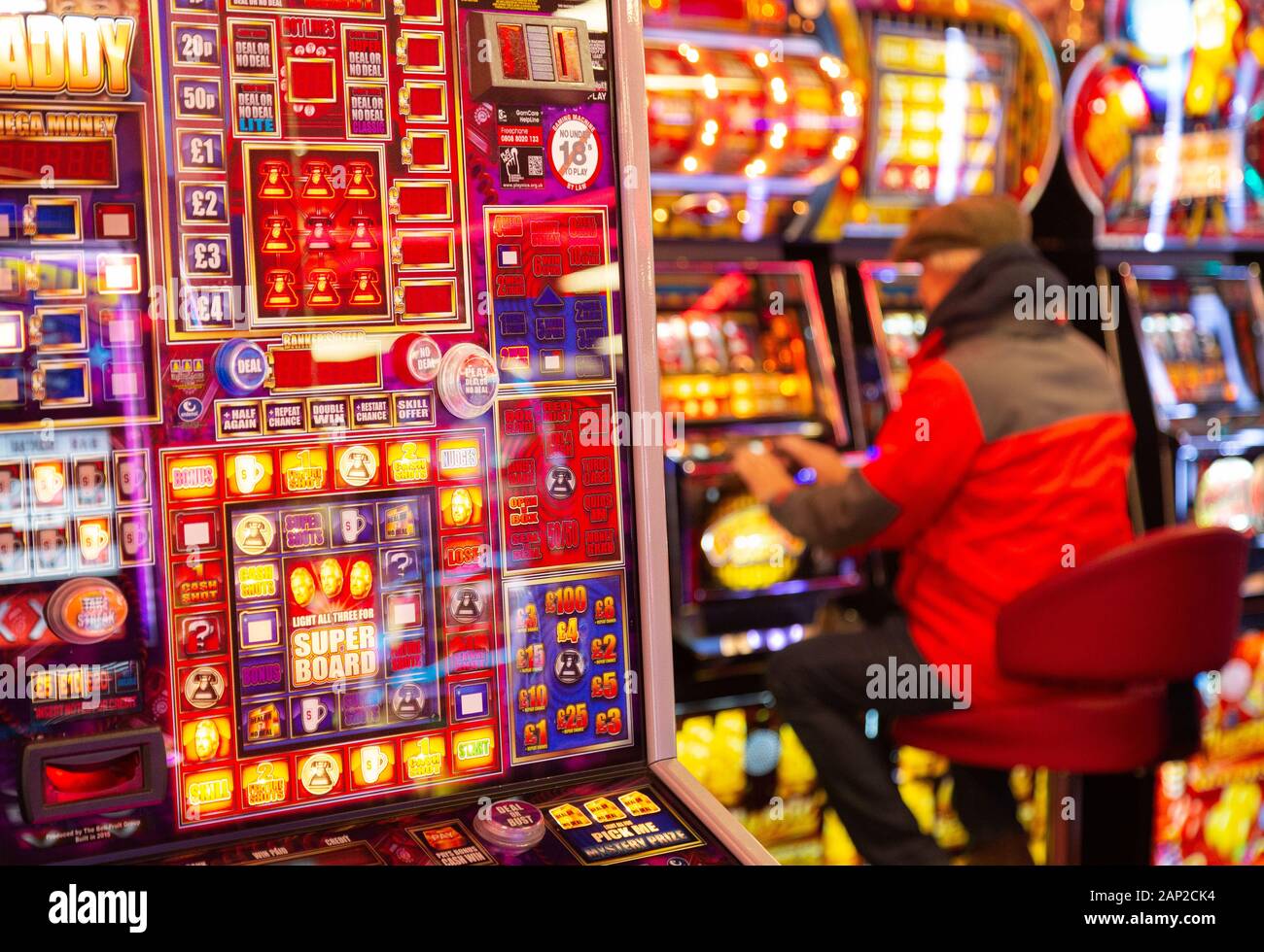 Gambling UK - a man playing slot machines in a casino, example of a gambling lifestyle; Skegness Lincolnshire England UK Stock Photo