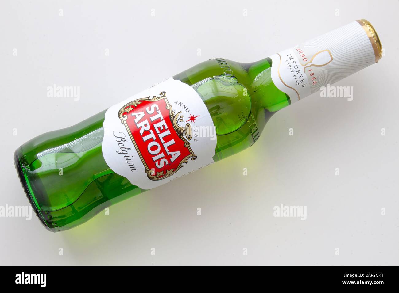 A Stella Artois beer bottle lay down on a white table Stock Photo