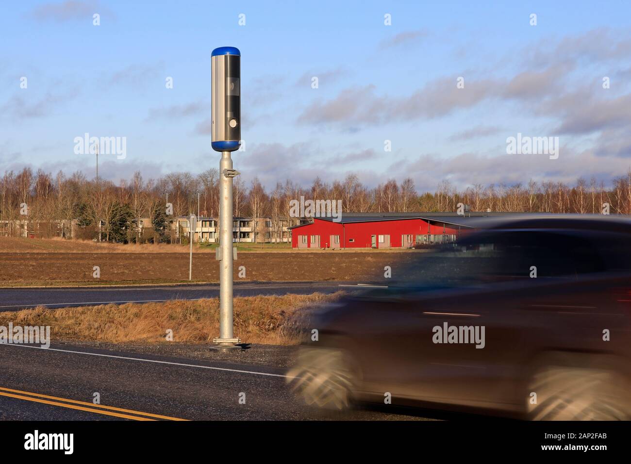 Car approaching a roadside speed camera on a sunny day of winter. Long exposure to blur the vehicle. Stock Photo