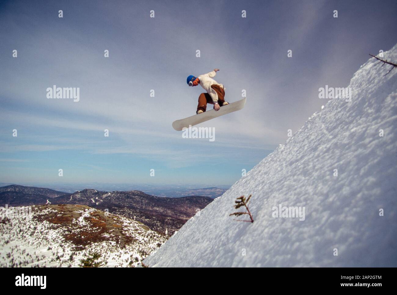 Snowboarder jumping off a large cliff in the backcountry in Stowe Vermont USA Stock Photo