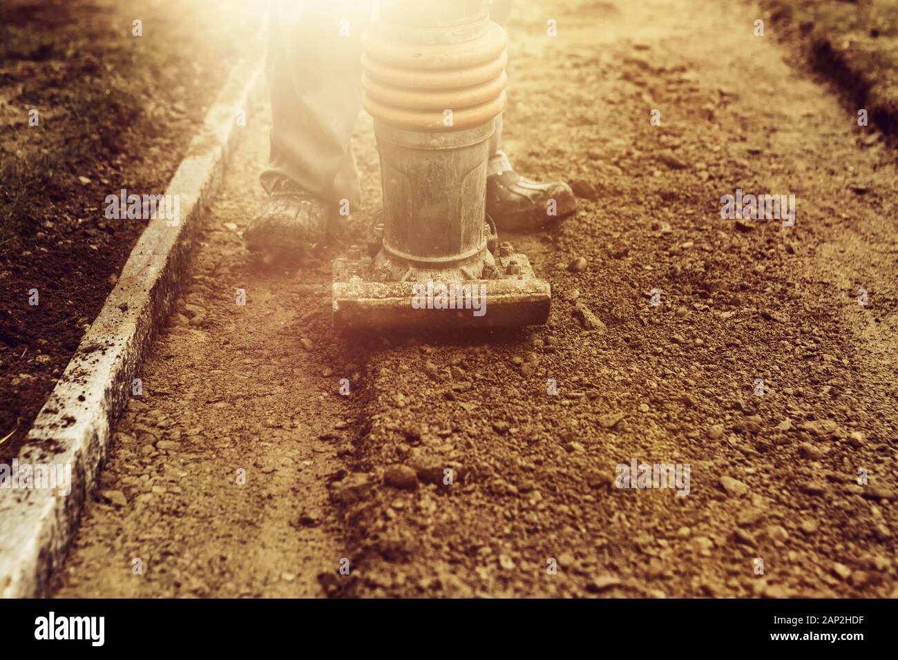 Stamping soil with rammer to build the garden path in the evening sunshine Stock Photo