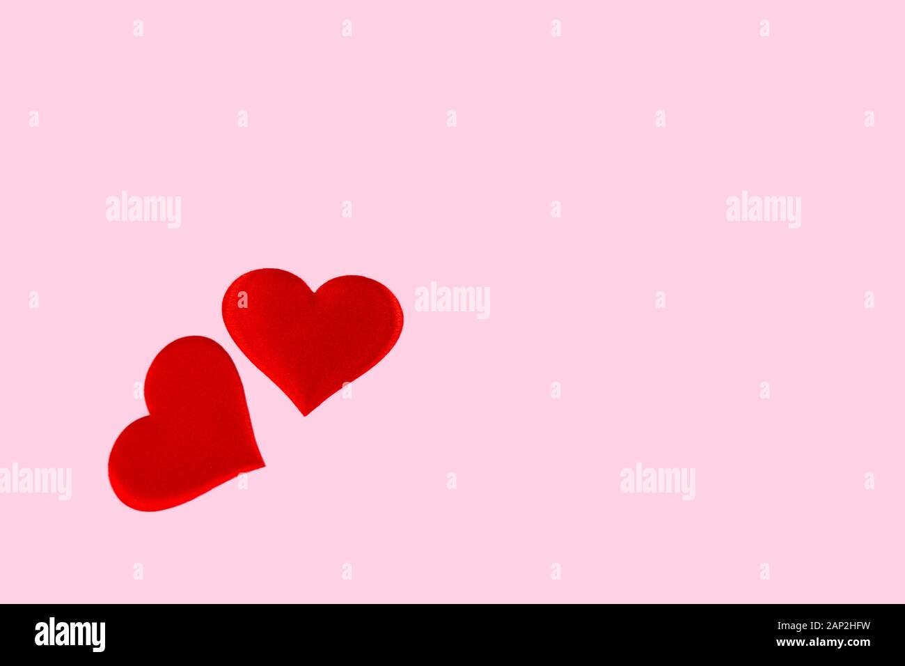 red hearts scattered on a pink background with free space for text ...