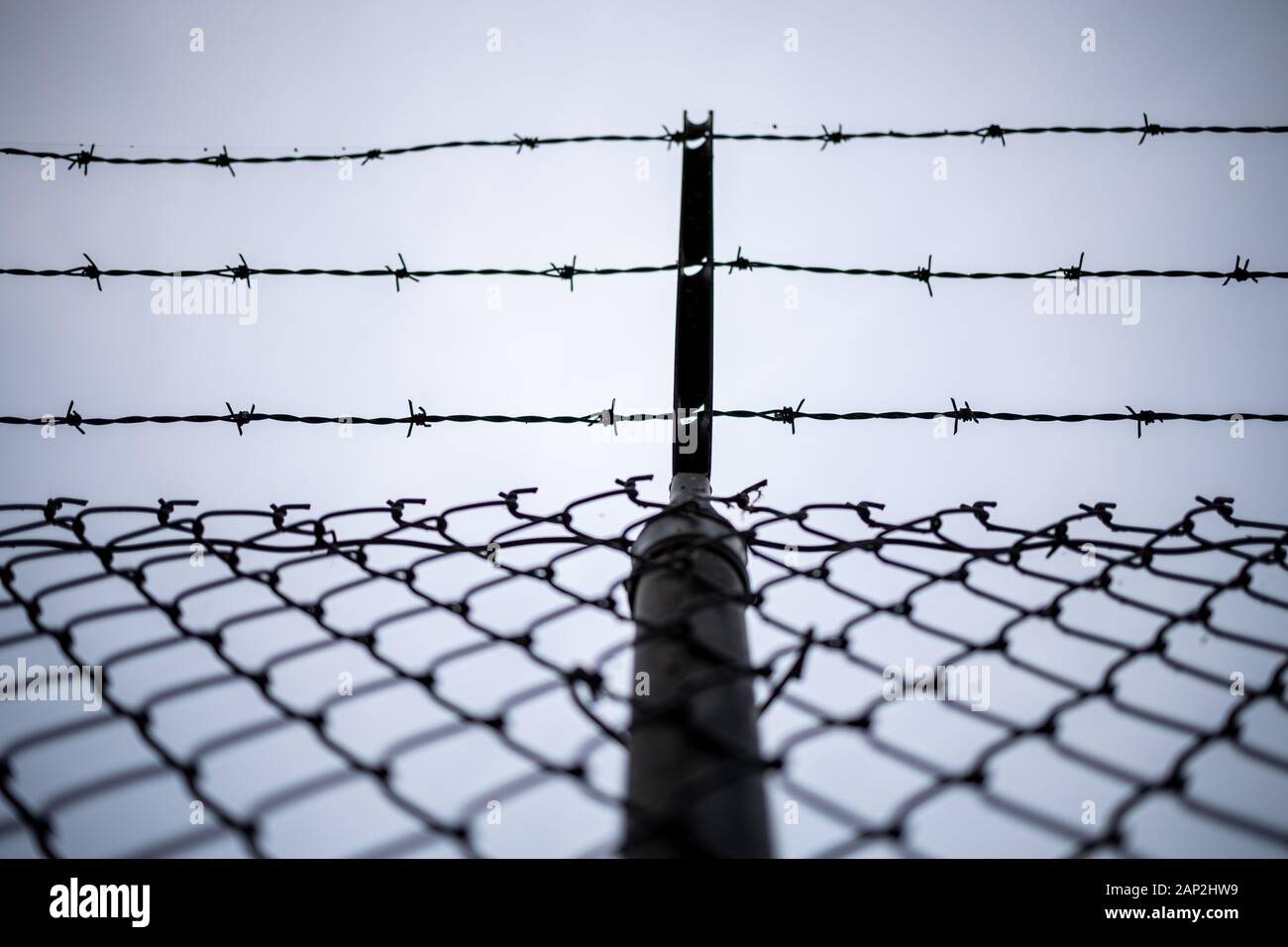 Tall fence with barbed wire anti climb strands on top in a cleared line