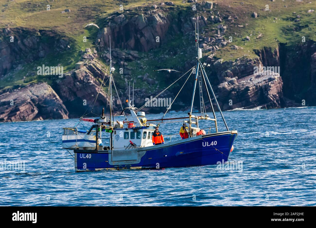 Fishing trawler and two fishermen fishing off the coastline of Ullapool in the Highlands of Scotlands, pre-Brexit.  Horizontal.  Space for copy. Stock Photo