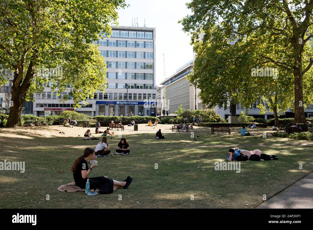 People sitting on grass and eating in Cavendish Square, Marylebone, City of Westminster, London England Britain UK Stock Photo
