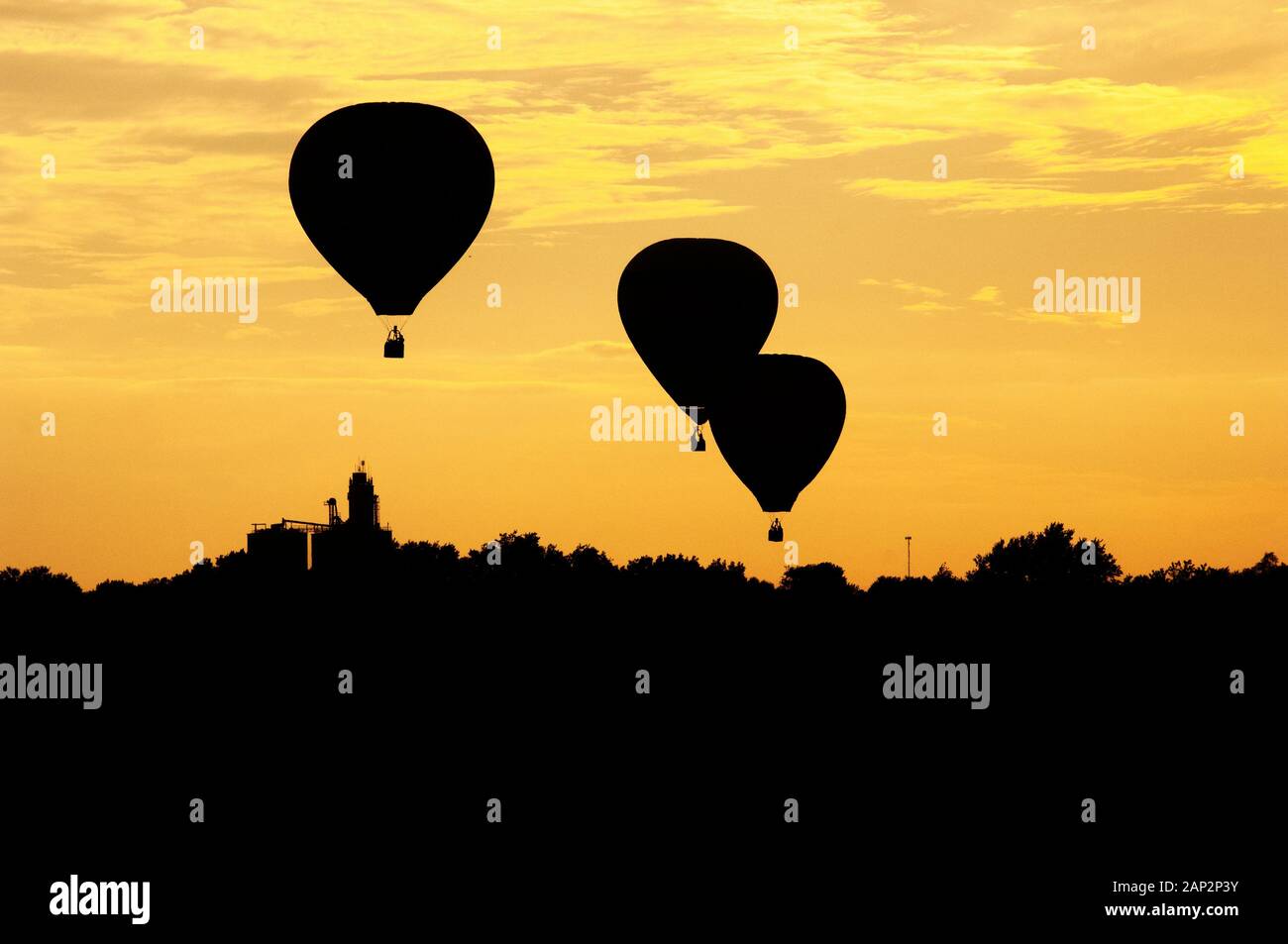 Three hot air balloons are silhouetted at sunset as the float above an ...