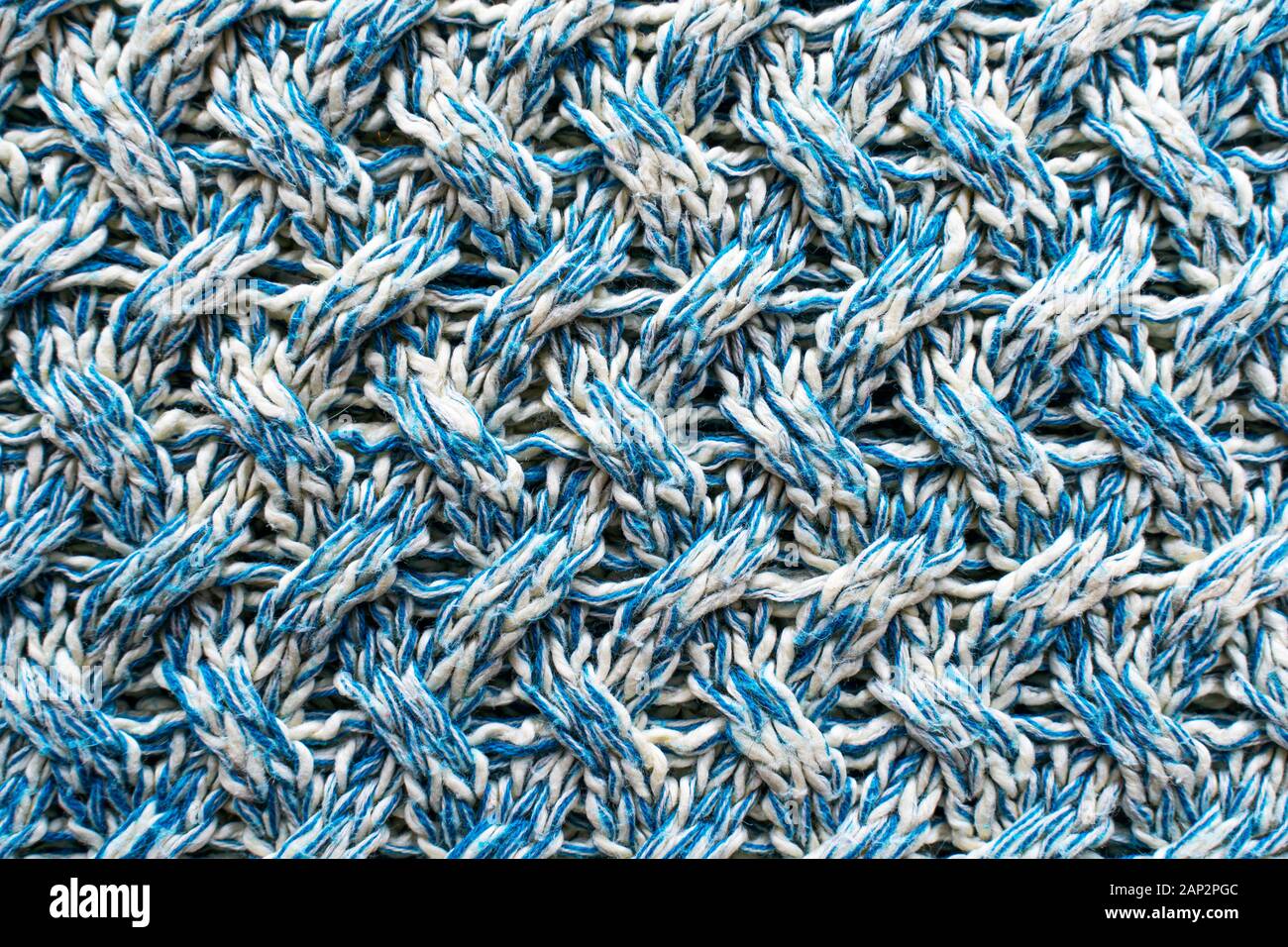 Blue and white texture of a knitted woolen fabric with a patterned weave. Sweater background Stock Photo