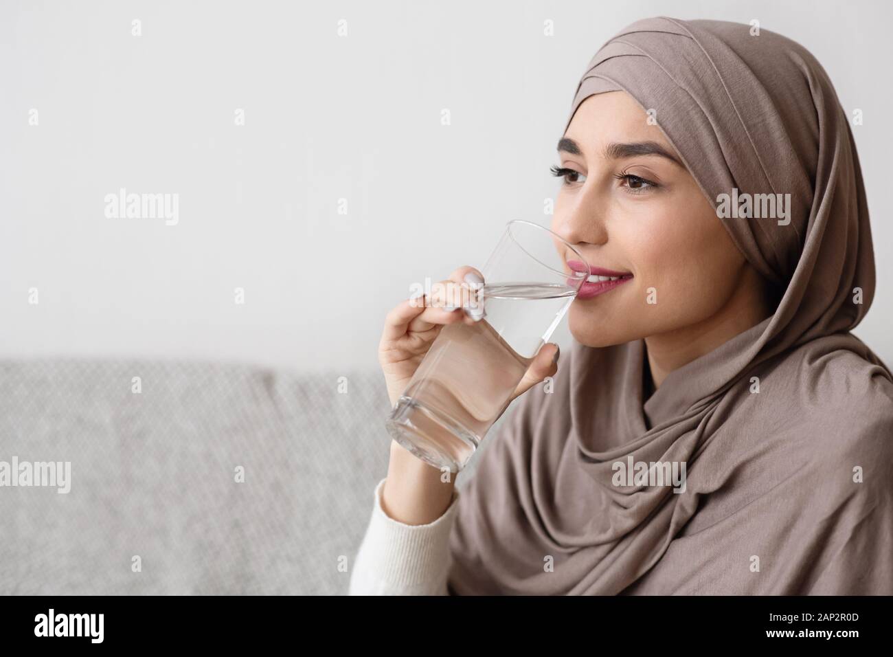 Young arabic woman in hijab drinking water from glass at home Stock ...