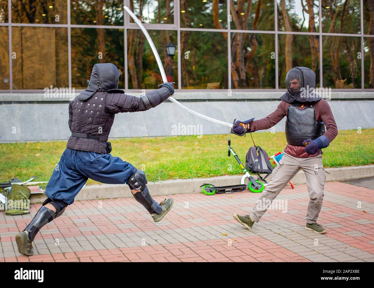 Two armed men lead a sword fight, a medieval fight, at a fun medieval tournament. Sports competitions. Gladiator fights. Stock Photo