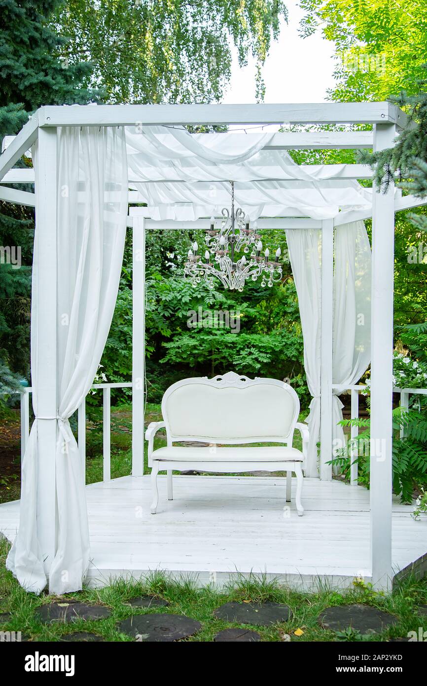 Summer elegant elegant gazebo in the lush gardens. Exquisite classic sofa  gazebo with white curtains fresh garden Stock Photo - Alamy