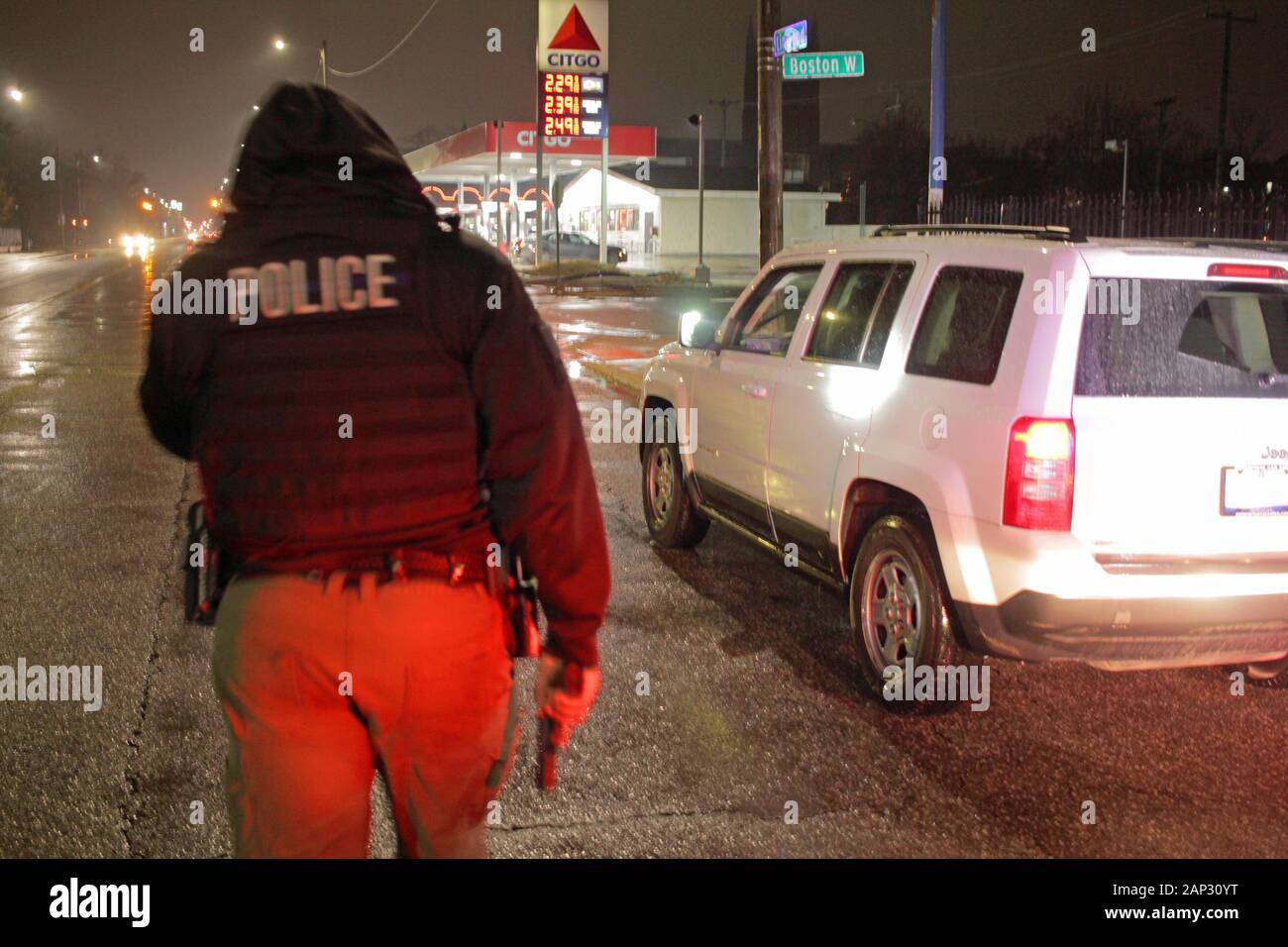 A Detroit police officer, holding his gun in his hand, approaches a car during a stop, Detroit, Michigan, USA Stock Photo