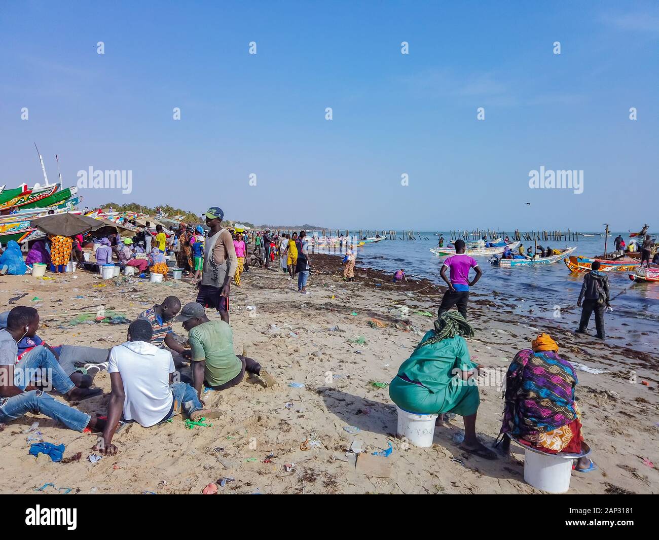 MBour, Senegal- April 25 2019: Unidentified Senegalese men and women waiting for the fishermen at the fish market in the port city near Dakar. There Stock Photo