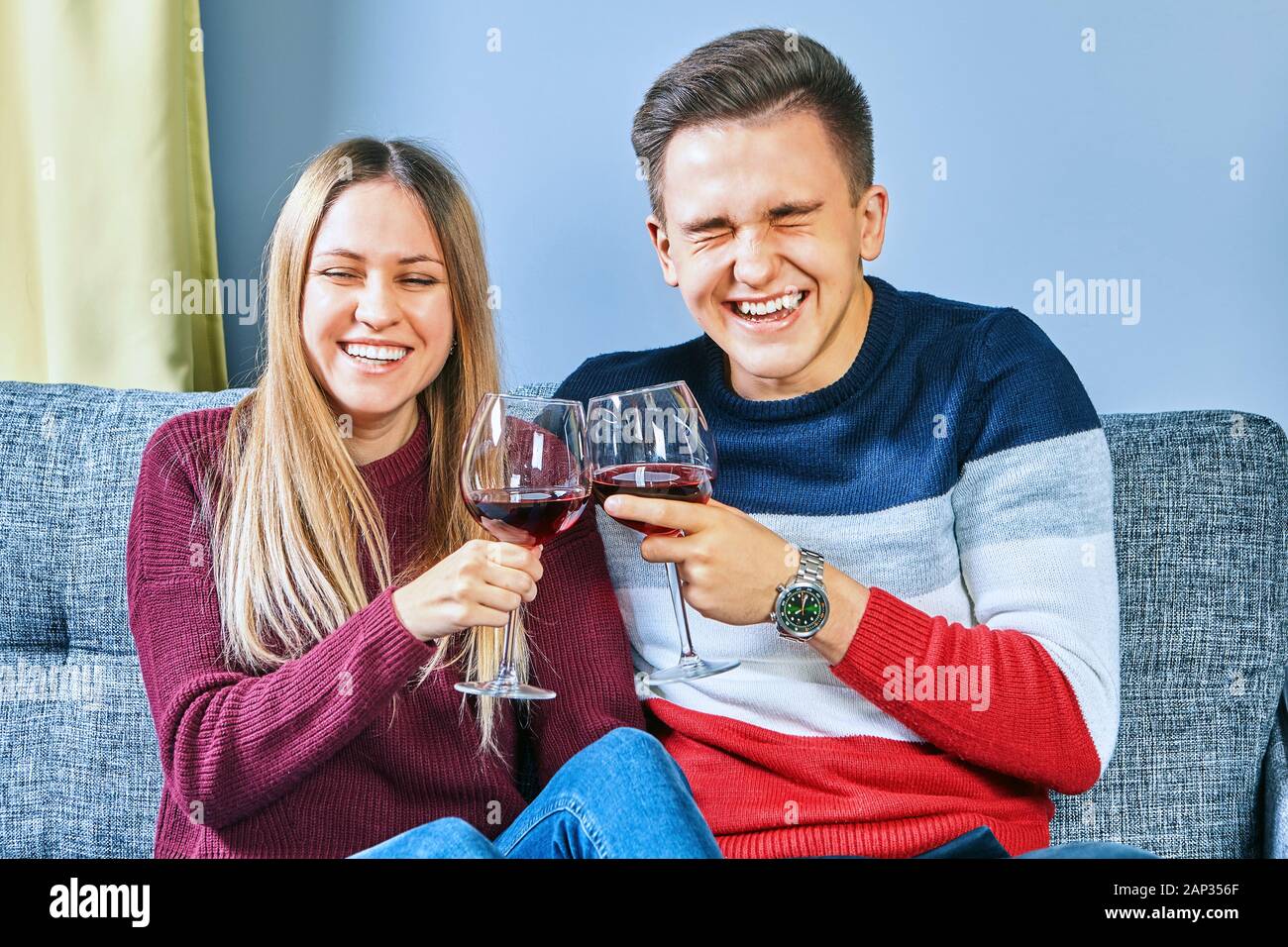 Happy couple drinking together. Drunk on the university campus, a young man and woman drink alcohol in a dorm room. Drunken students clink buckets and Stock Photo