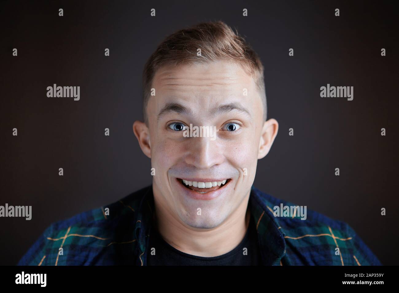 Emotions of joy and surprise on the face of a young man aged just over 20 years old while watching a funny movie in the cinema or on the TV screen. He Stock Photo