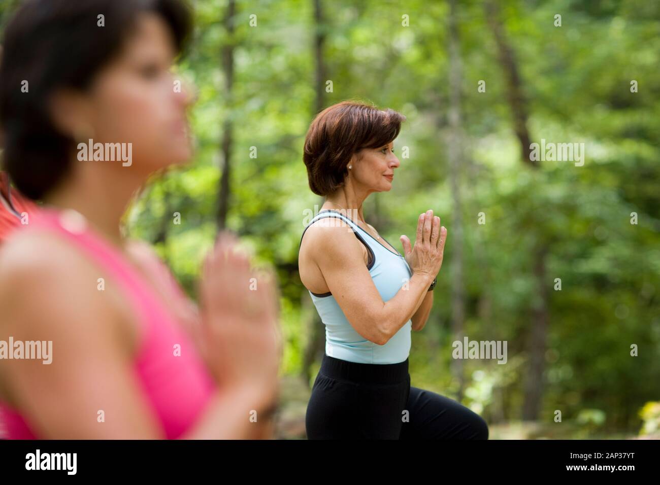 Middle aged women doing yoga in forest Stock Photo
