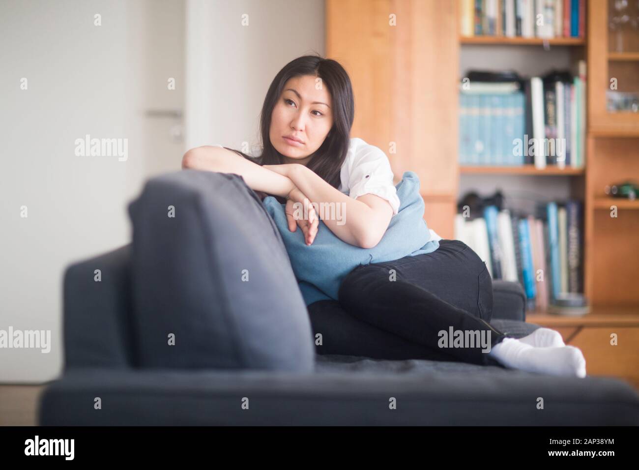 young woman at home in a living room lying on a couch revised Stock Photo