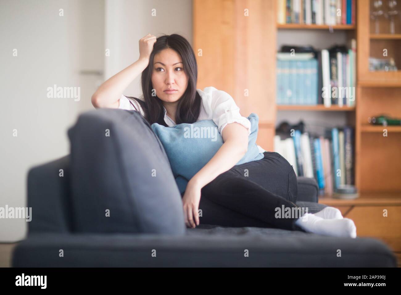 young woman at home in a living room lying on a couch revised Stock Photo