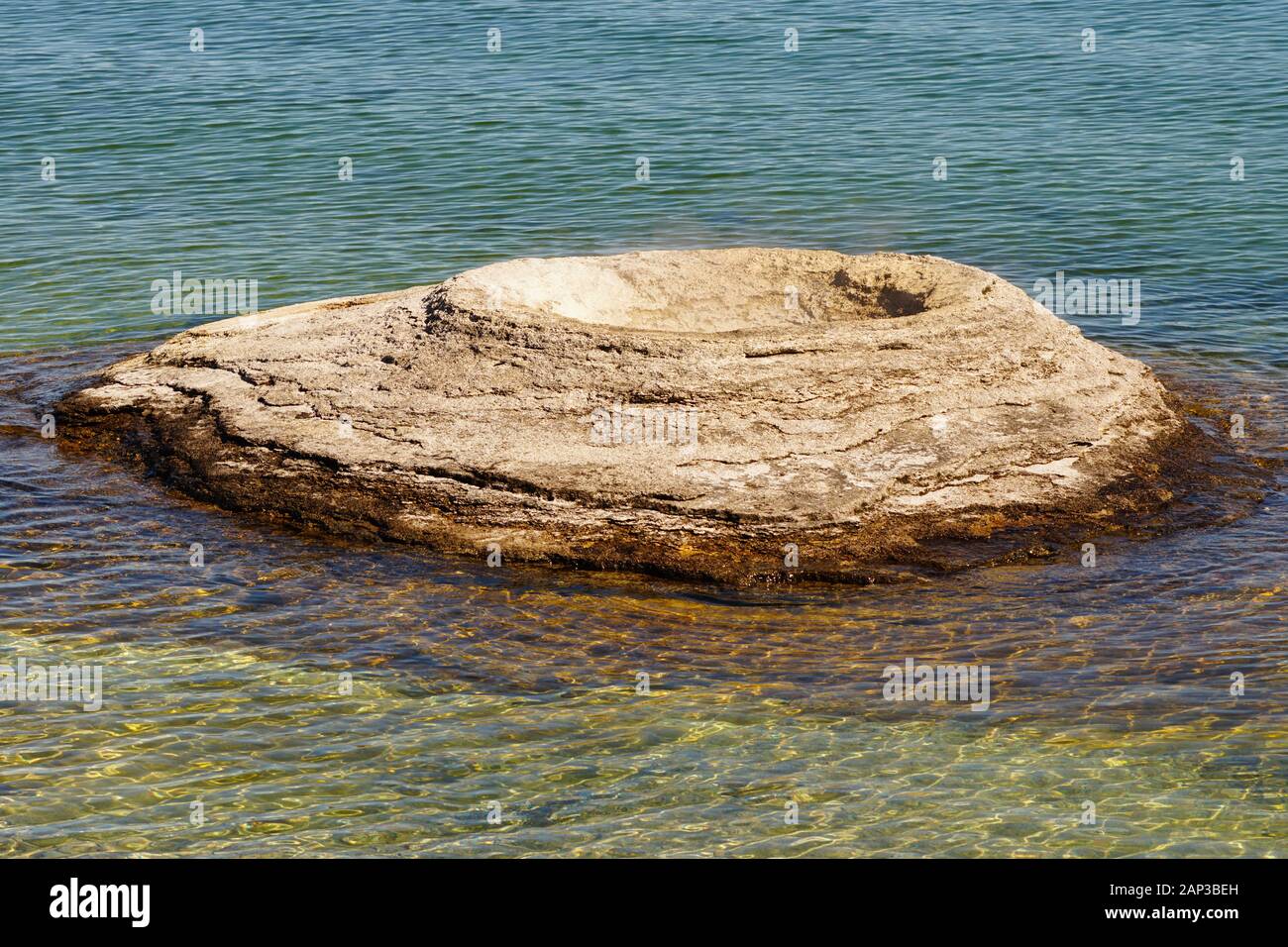 Steam comes from a thermal mud pot in the shallows of Yellowstone Lake in Yellowstone National Park Stock Photo