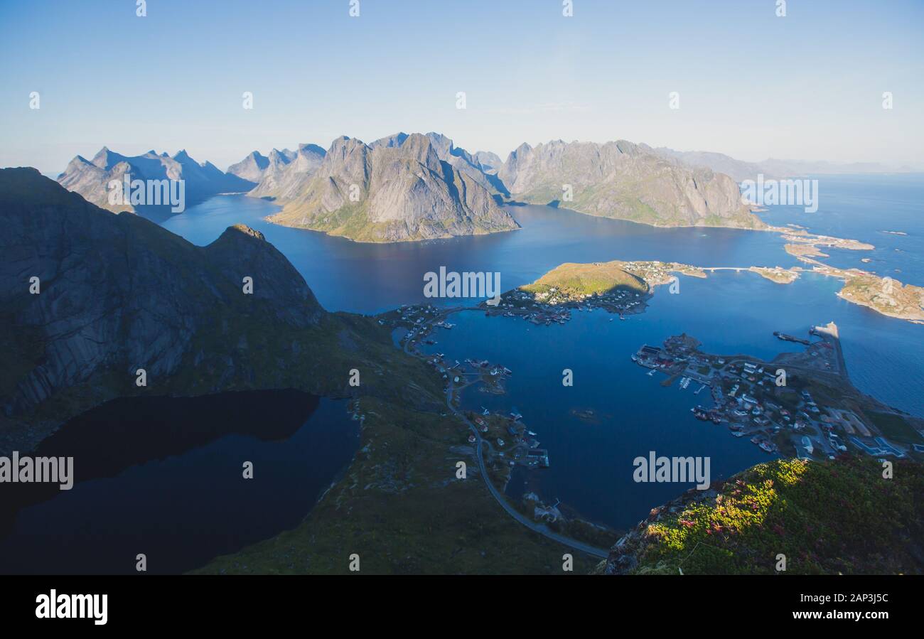 Beautiful norwegian landscape with famous top peak Reinbringen, Lofoten Islands, with a group of hikers tourists, and with a view on famous Reine city Stock Photo