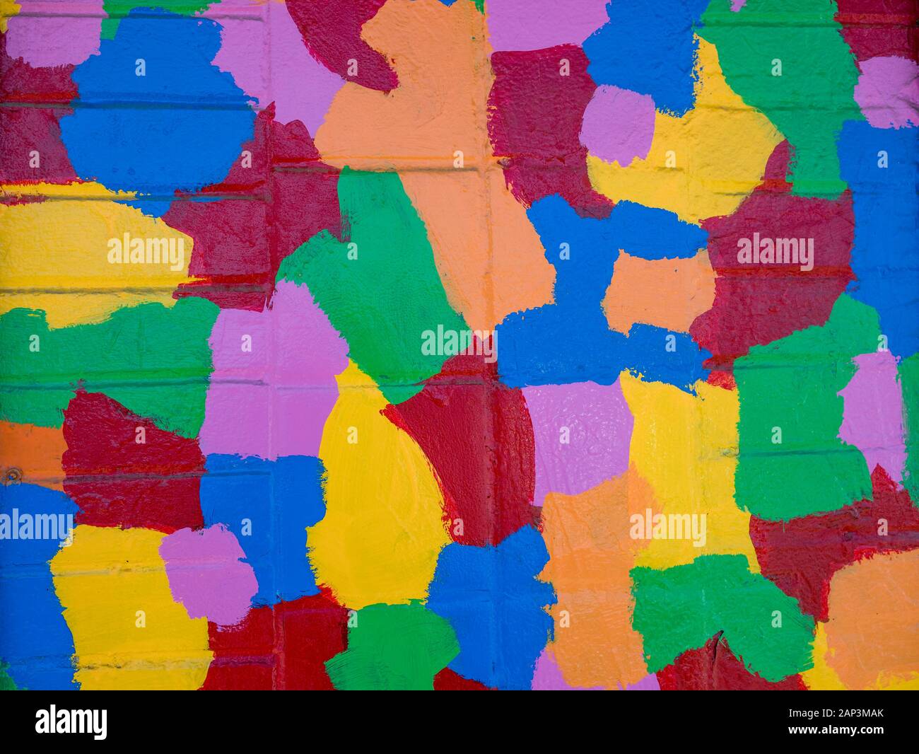 Colorful, painted, geometric puzzle shapes on urban brick wall Stock