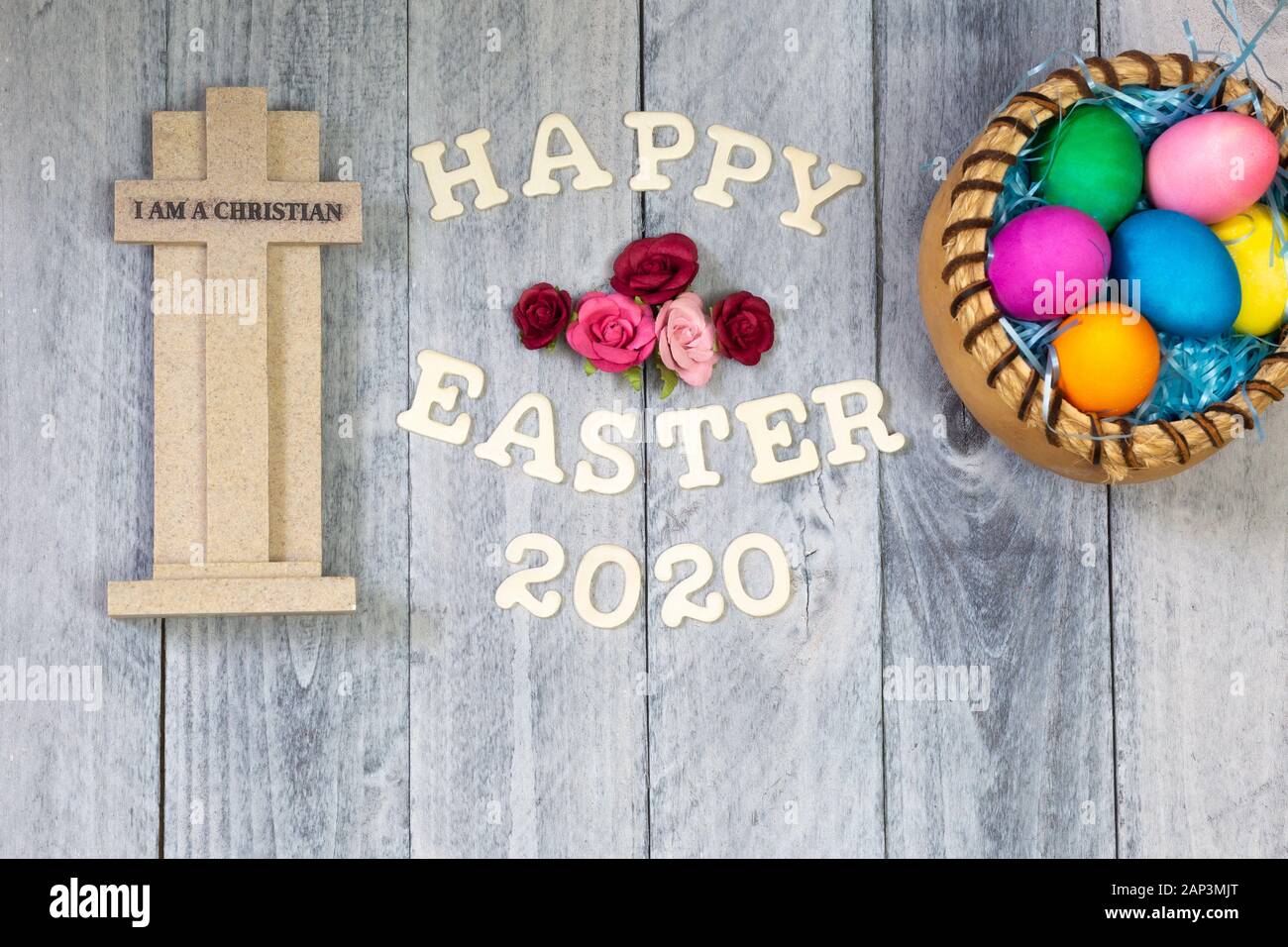 Christian Cross, flowers, Easter eggs, on a wood background with Happy Easter 2020 Stock Photo