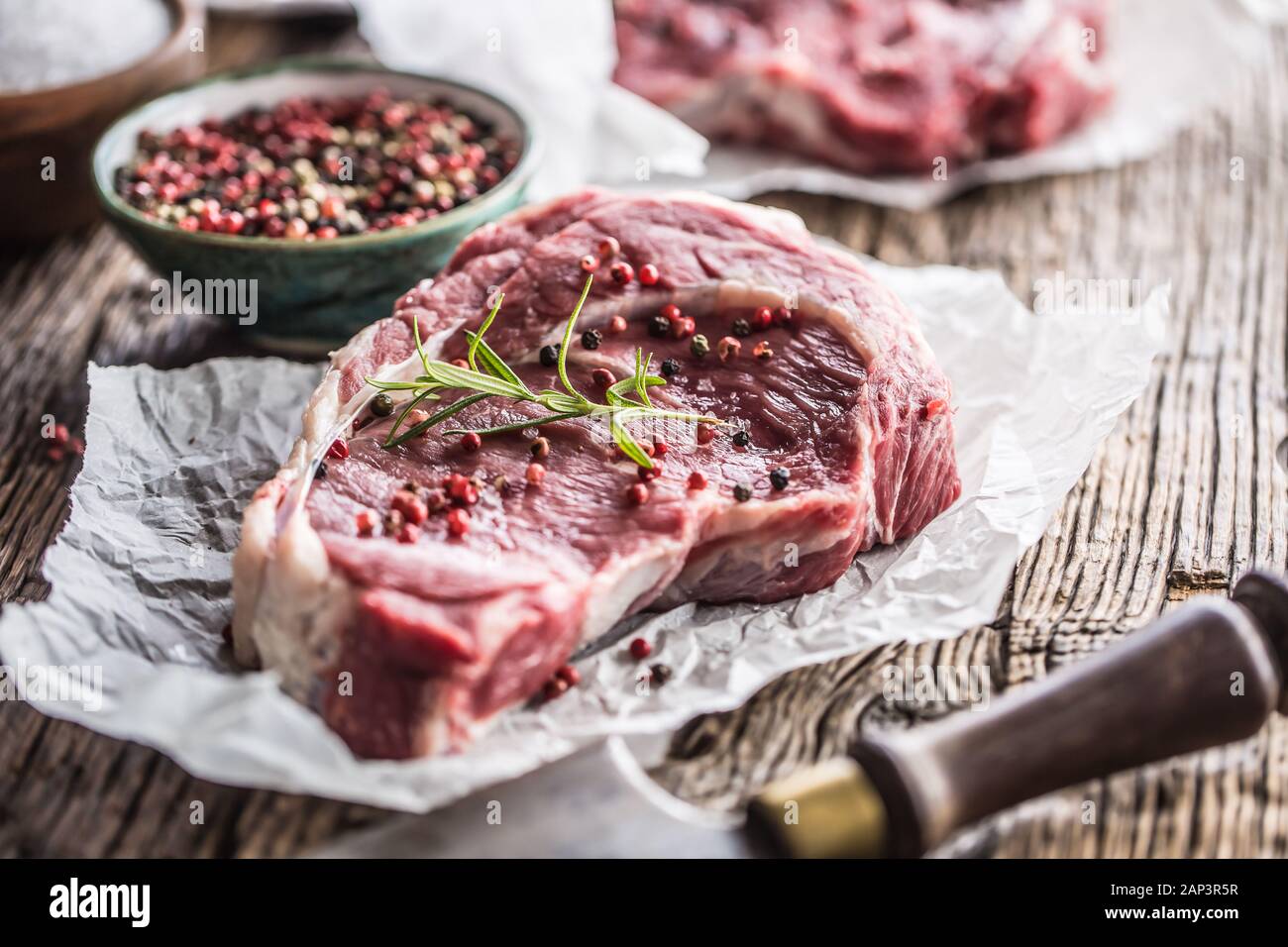 Beef Rib Eye steak with salt pepper and rosemary on wooden table Stock Photo