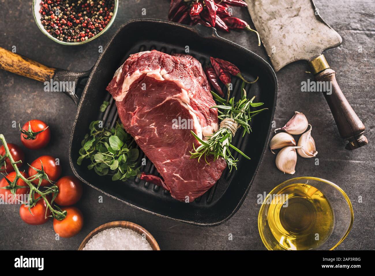Beef ribe eye steak in grill pan with rosemary oregano salt pepper spices  garlic and tomatoes Stock Photo - Alamy